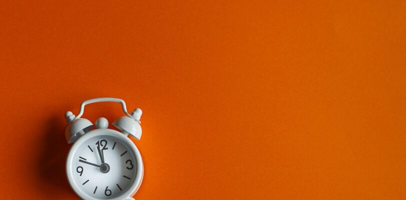 An alarm clock appears on an orange background.