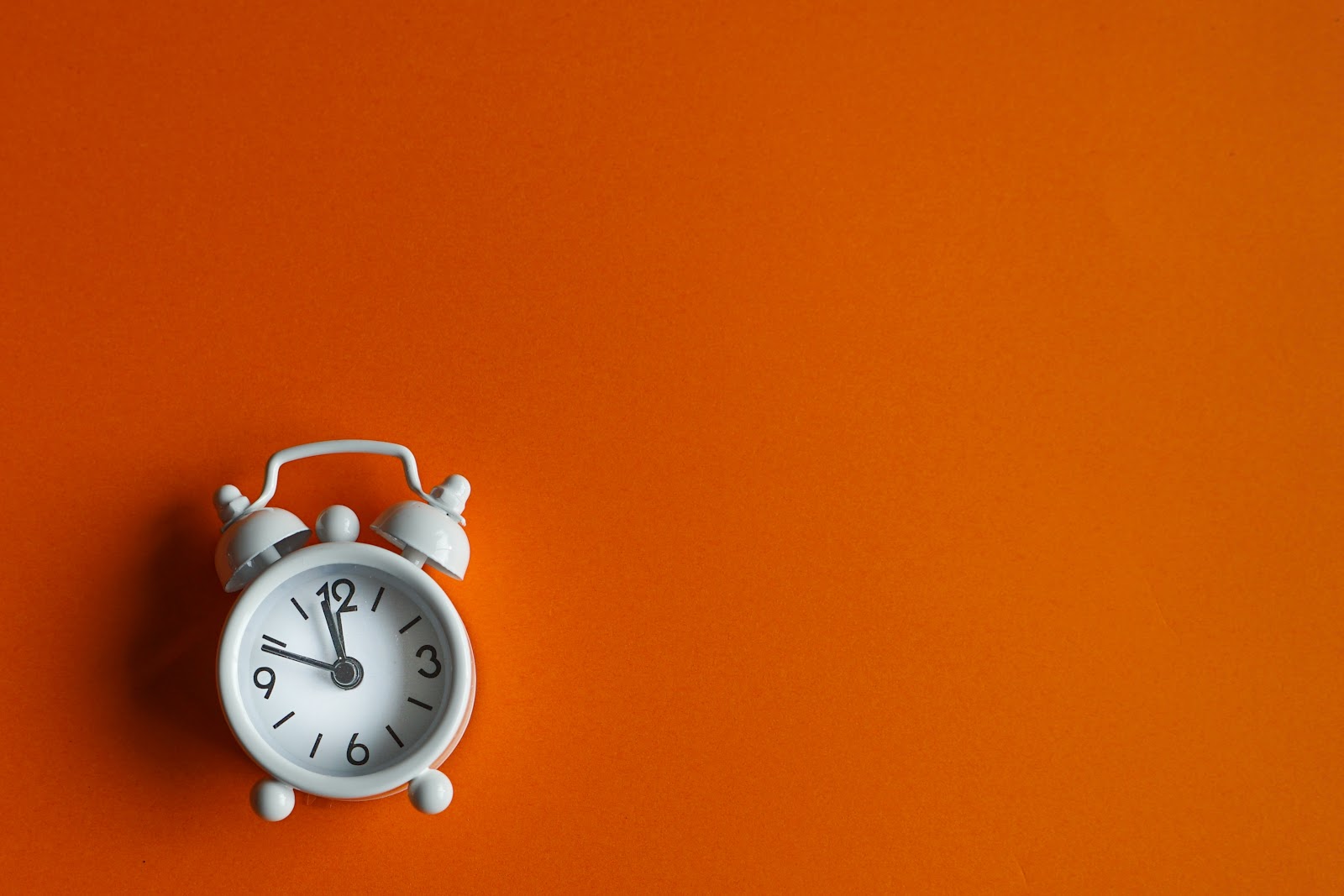 An alarm clock appears on an orange background. 