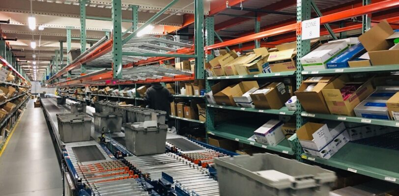 warehouse shelves are pictured as a box moves down a conveyor belt