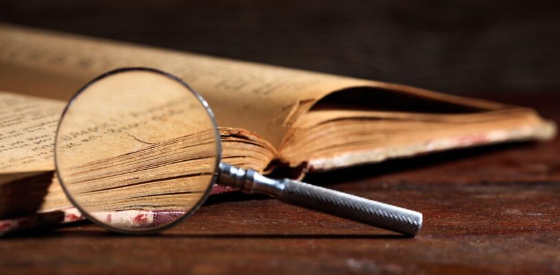 a magnifying glass sits next to a historic book